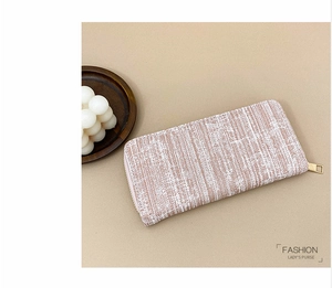 Detail view of pink beige striped long purse with woven texture and gold zipper closure