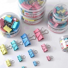 Macro shot of assorted colorful binder clips in various sizes and transparent containers