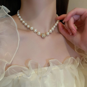 Gros plan d'un collier de perles vintage français avec fermoir sphère dorée sertie
