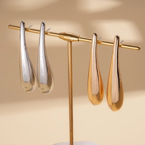 Polished metallic teardrop earrings in gold and silver finishes on a display stand