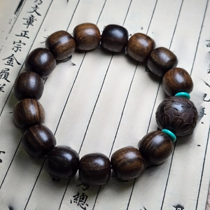 Détails de perles de bois d'agar foncé avec espaceurs turquoise sur calligraphie ancienne