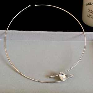 Detail of silver minimalist metal choker with crystal inlay on a gray velvet tray