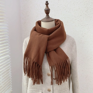 Close-up of brown cashmere-style scarf with fringe on a mannequin in beige coat