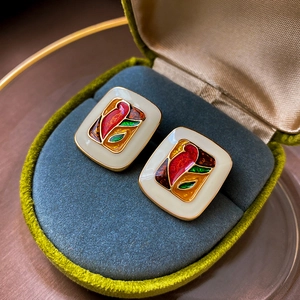 Close-up of vintage square oil painting earrings in a green velvet jewelry box