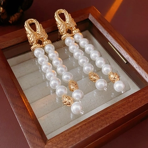Detailed view of vintage gold hollow earrings with elegant double-layered pearl tassels