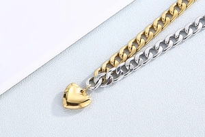 Close-up of gold and silver stainless steel Cuban link bracelets with a heart pendant