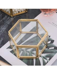 Detail of hexagonal gold brass glass jewelry box on marble with decorative elements