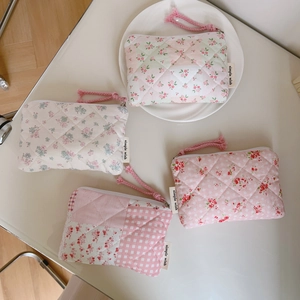 Detailed flat lay of four assorted floral quilted cotton mini pouches on white surface