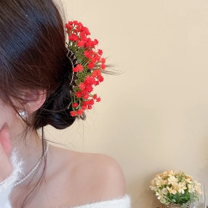 Detail showing the red flower hair claw clip worn on an elegant braided hairstyle