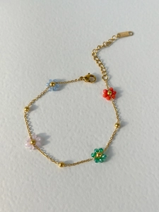 Detail of gold chain bracelet with colorful pink, blue, and green flower beads