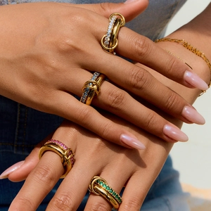 Stacked gold zircon rings with colorful gemstones worn on hand in bright outdoor sunlight