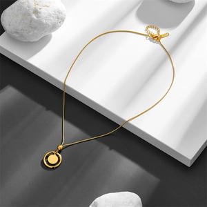 Gros plan du collier trèfle à quatre feuilles doré avec chaîne serpent raffinée