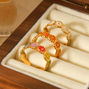 Three gold stainless steel daisy rings with colorful enamel on a velvet jewelry box