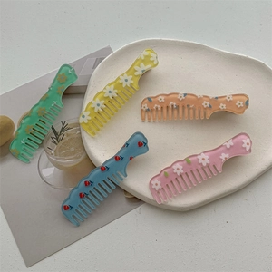Cute colorful mini comb hair clips with flower patterns on a decorative ceramic tray
