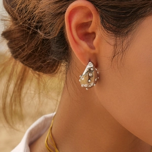 Close-up of teardrop earrings with white pearls and zircons on a model's ear
