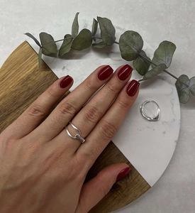 Detailed view of silver asymmetric dual-line open ring on finger with lifestyle decor