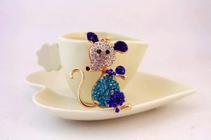 Detailed view of a gold mouse keychain featuring blue rhinestones on white cup background