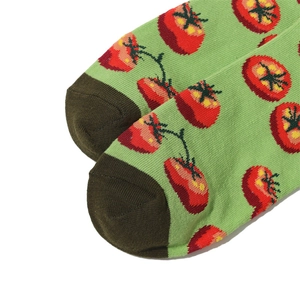 Close-up of green cotton crew socks with red tomato patterns and contrast toe detail