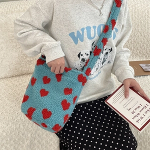 Detail of blue plush leopard print shoulder bag with red hearts shown on soft fabric