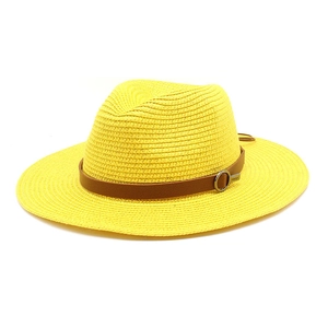 Detailed texture of yellow woven straw sun hat with brown leather band and silver buckle