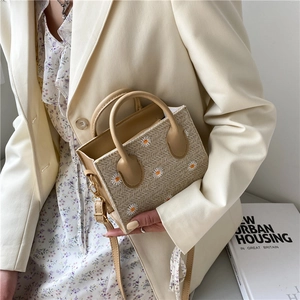 Handmade straw woven mini tote with daisy embroidery and adjustable leather strap