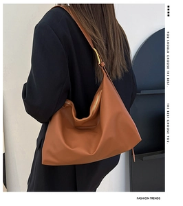 Detail view of large brown hobo bag with zip closure on a model shoulder