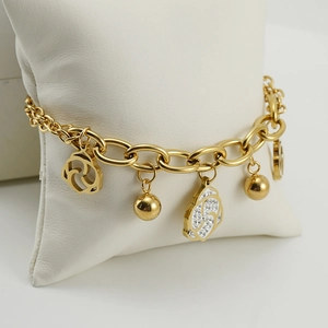 Gold stainless steel link bracelet with rose charms and crystals on a display pillow