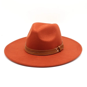 Close-up of orange wool fedora hat with brown faux leather band and metal rivet detail
