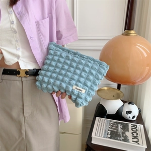 Blue bubble textured cloud makeup bag held by model for a size and style demonstration