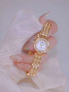 Close-up of elegant gold ladies watch with crystal setting and white pearlescent dial