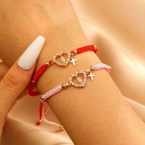 Detail of woven bracelet with gold Virgin Mary charm and sparkling white zircon heart