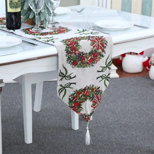Knitted Christmas table runner with festive wreath patterns and white tassels on a table