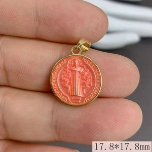 Macro shot of a 17.8mm round Saint Benedict medal pendant with orange enamel and gold finish