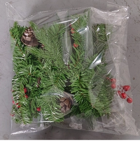 Detail of Christmas pine wreath with cones and berries inside transparent packaging