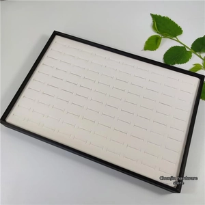 Macro shot of 100-slot jewelry display tray with white lining and black frame border