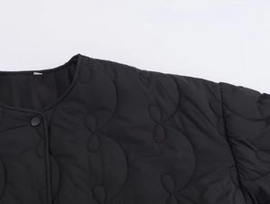Détail de la veste matelassée noire avec col rond et boutons-pression métalliques
