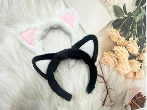 Dettaglio di cerchietti con orecchie di gatto in peluche bianco e nero su pelliccia