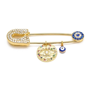 Detail of gold safety pin brooch with sparkling evil eye charms and rhinestone inlay
