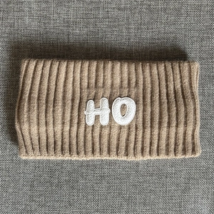 Macro detail of camel knitted sports headband with HO embroidery and ribbed texture
