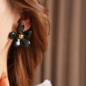 Close-up of vintage black flower earring with golden core worn by a model