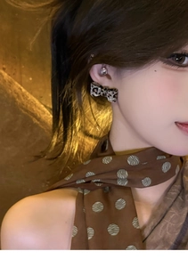 Close-up of leopard pattern bow earrings with sparkling rhinestones worn by a model