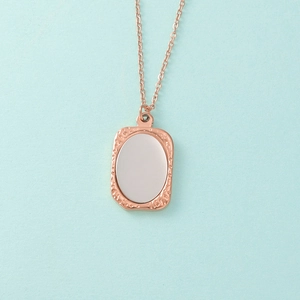 Detail van roségouden rechthoekige hanger met gepolijst zilveren ovaal inzetstuk