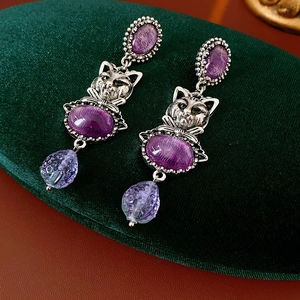 Macro shot of vintage silver cat head earrings with purple stone and faceted pendants