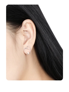 Detailed view of silver irregular heart earring with pearl accent on a female ear