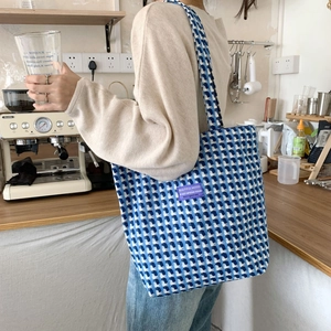 Blue and white woven pattern on a large capacity tote bag with purple fabric label detail