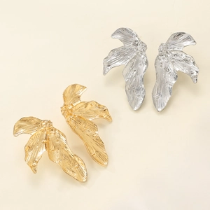 Macro detail of irregular pleated leaf earrings in polished gold and silver metal finishes