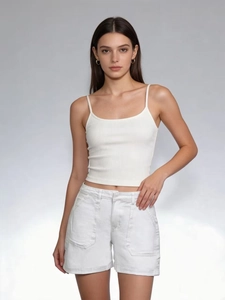 Dettaglio del top a costine bianco abbinato a pantaloncini di jeans a vita alta su modella