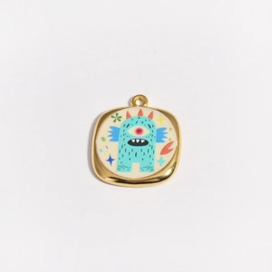 Détail du pendentif en or 18K avec monstre bleu de dessin animé et cornes rouges