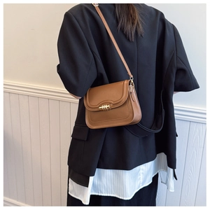 Close-up of brown vintage saddle bag with gold metal hardware worn with a black blazer