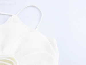 Detailed view of white strap top with 3D layered flower petals and smooth fabric texture